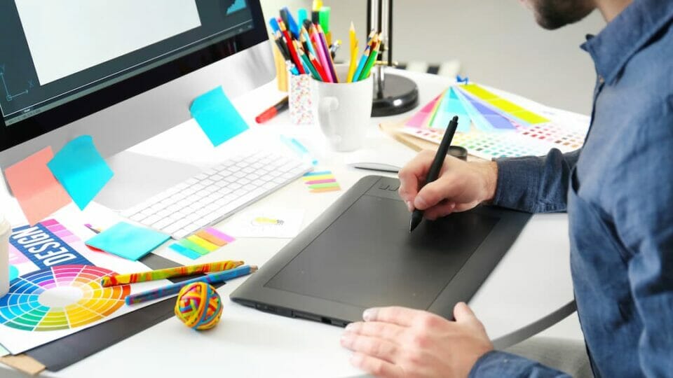 A man is drawing on a tablet at his desk.