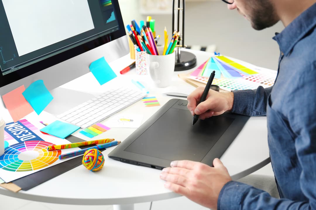 A man is drawing on a tablet at his desk.